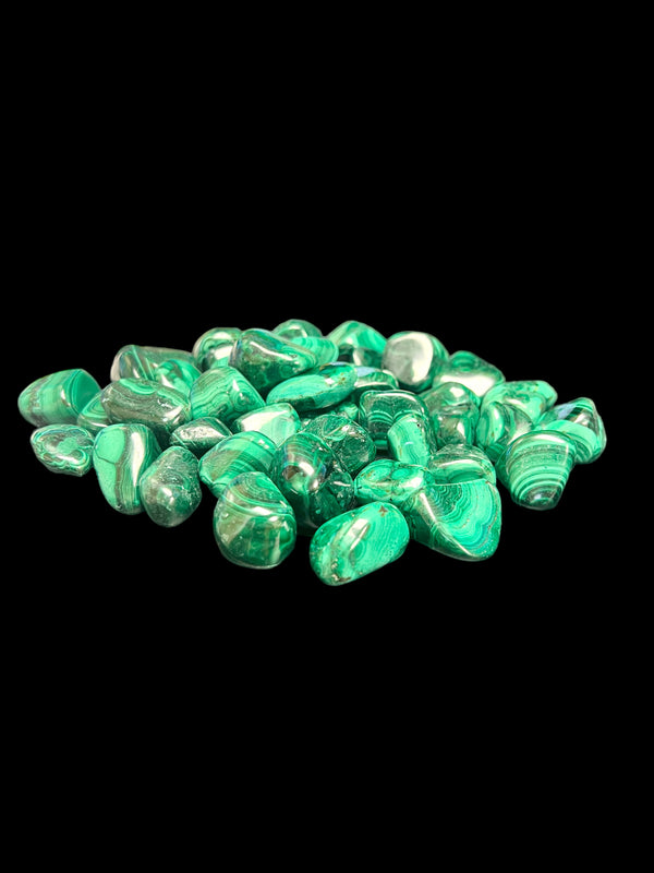 Malachite Tumble Polished Stones spread out with a black background.